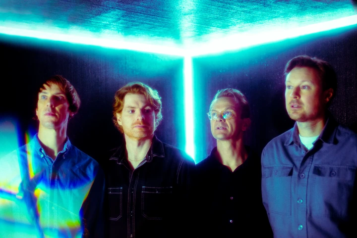 Django Django beneath coloured fluorescent lights