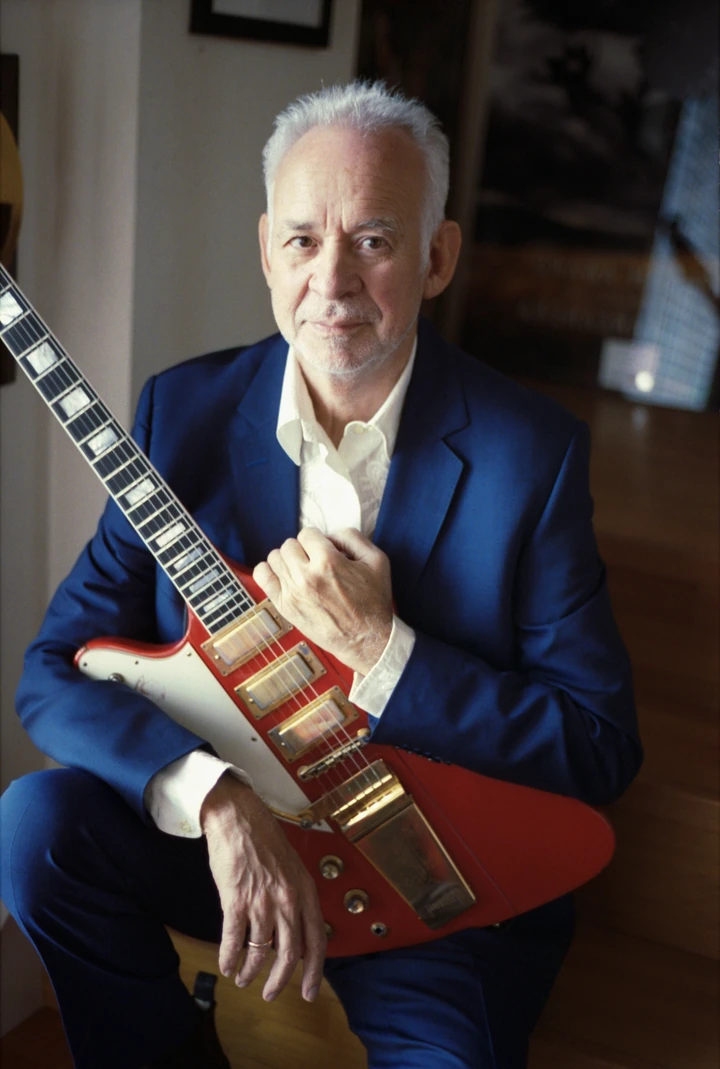 Phil Manzanera holding a guitar in natural light