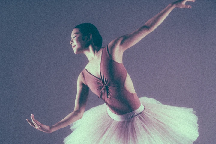 Dancer extending an arm under coloured studio lighting