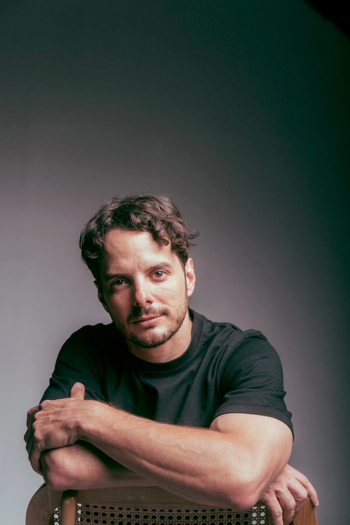 Seated artist portrait against a dark studio backdrop