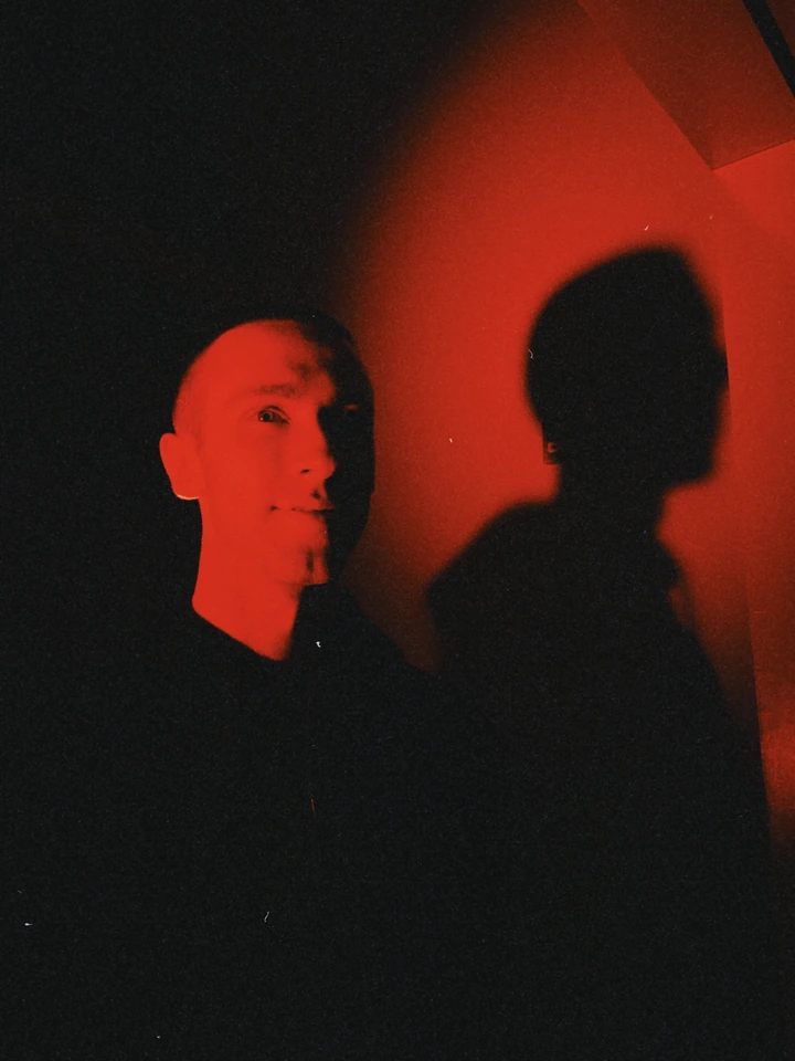 Red-lit portrait and a shadow on a wall