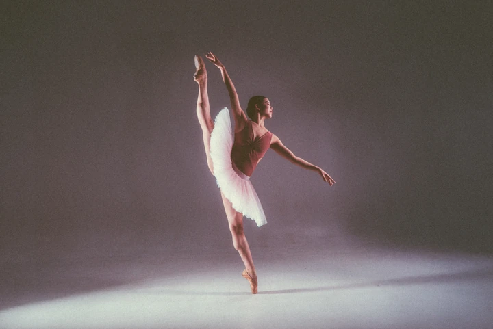 Dancer in a white tutu extending a leg in a studio